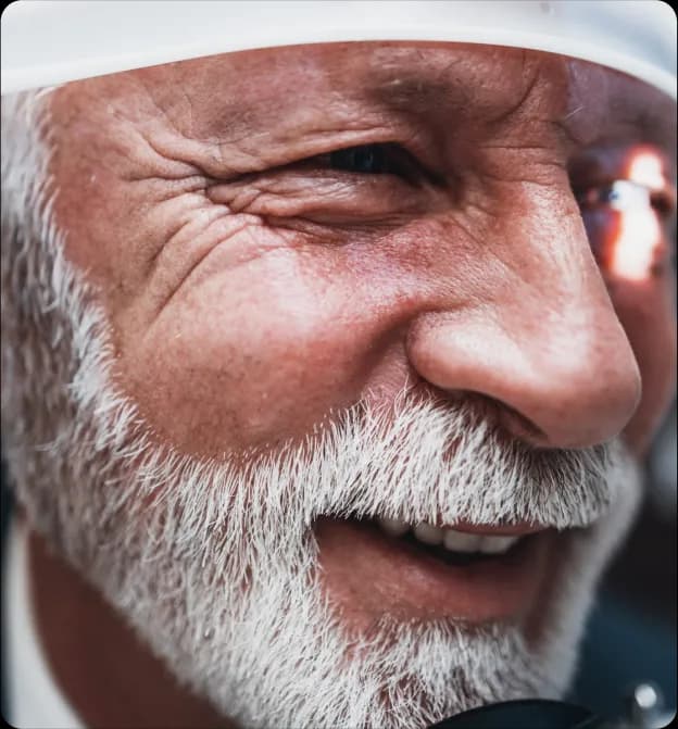 Close-up of an elderly man smiling while undergoing an eye examination with a light focused on his eye.