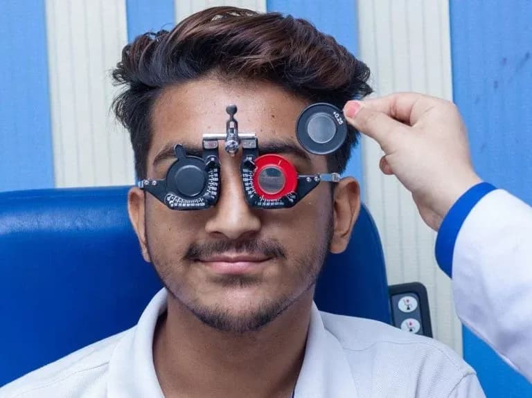 Person undergoing an eye test with a trial frame and lenses being adjusted.