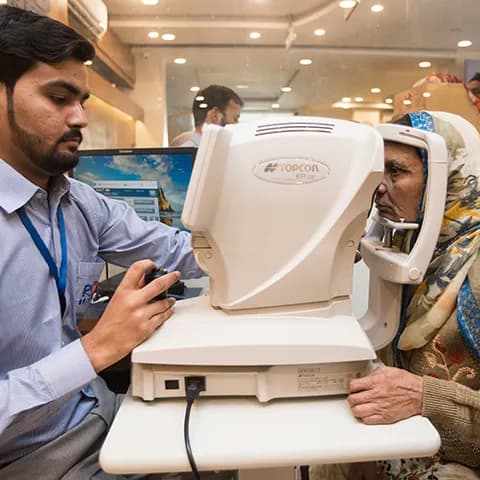 A doctor conducting an eye examination using a Topcon machine on an elderly woman